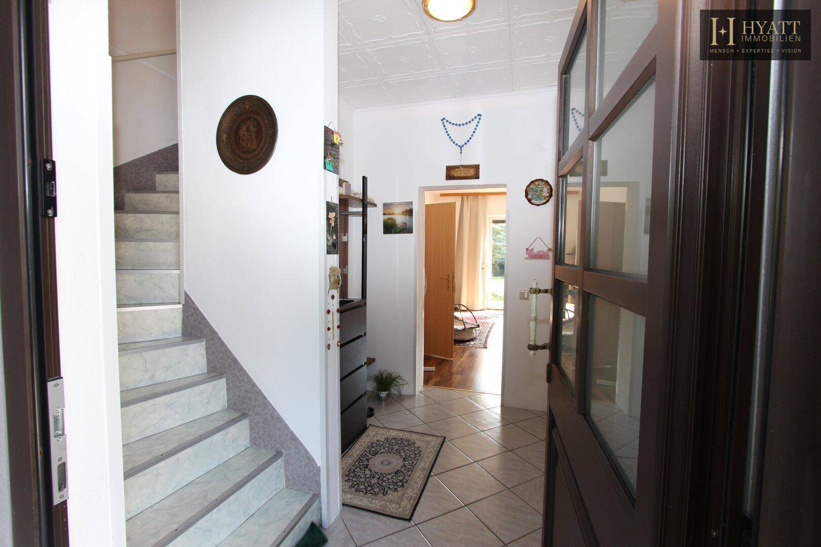 Heller Eingangsbereich mit Fliesenboden, Treppe und Zugang zu weiteren Räumen.