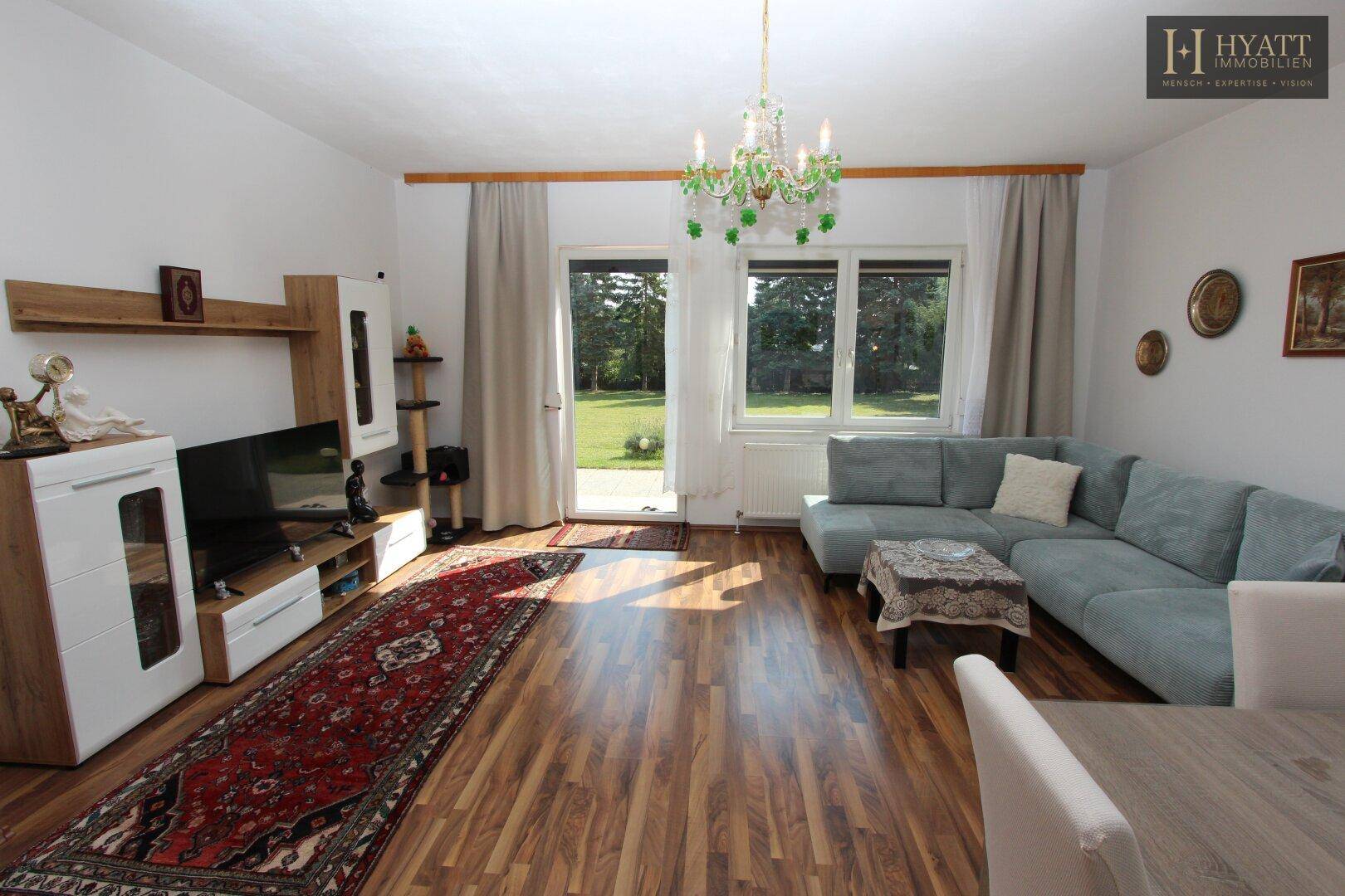 Helles Wohn- und Esszimmer mit Holzboden, gemütlichem Sofa und Zugang zum Garten.