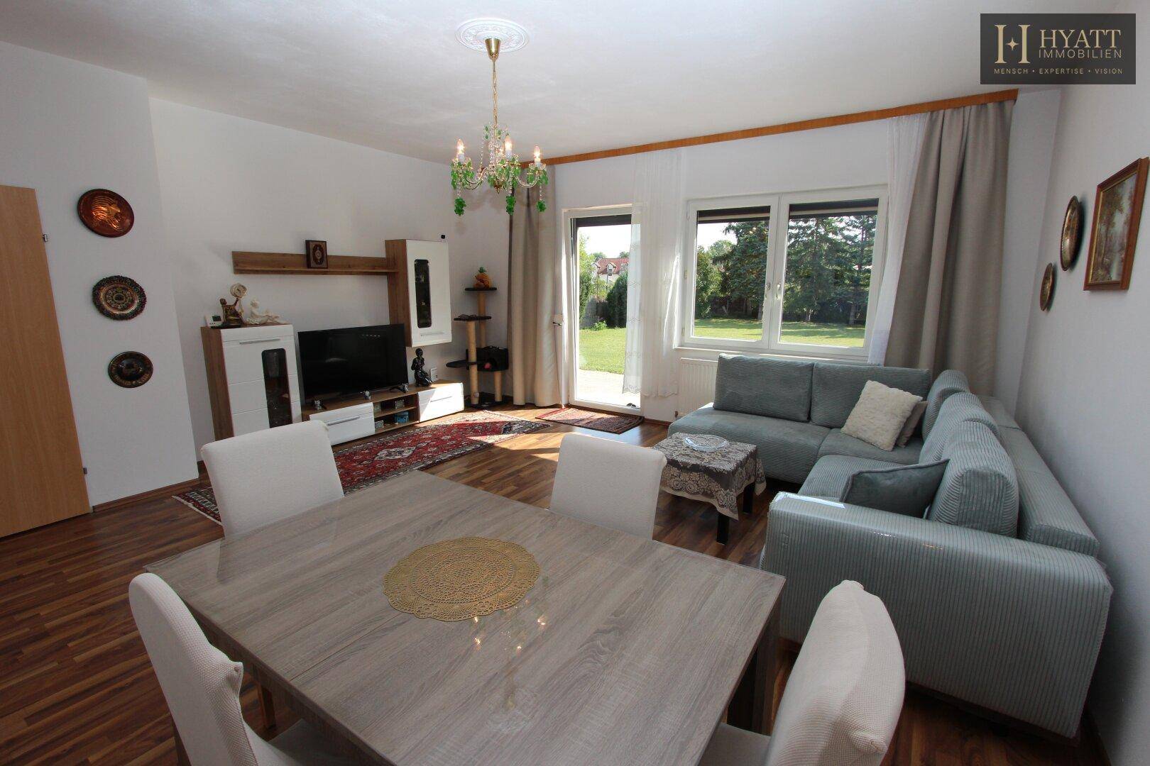 Gemütlicher Wohn- und Essbereich mit Holzboden, Sofa und Esstisch, ideal für Familien.