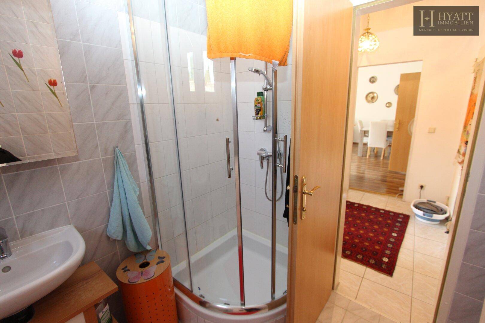Badezimmer mit Fliesenboden, Waschbecken und Duschkabine.