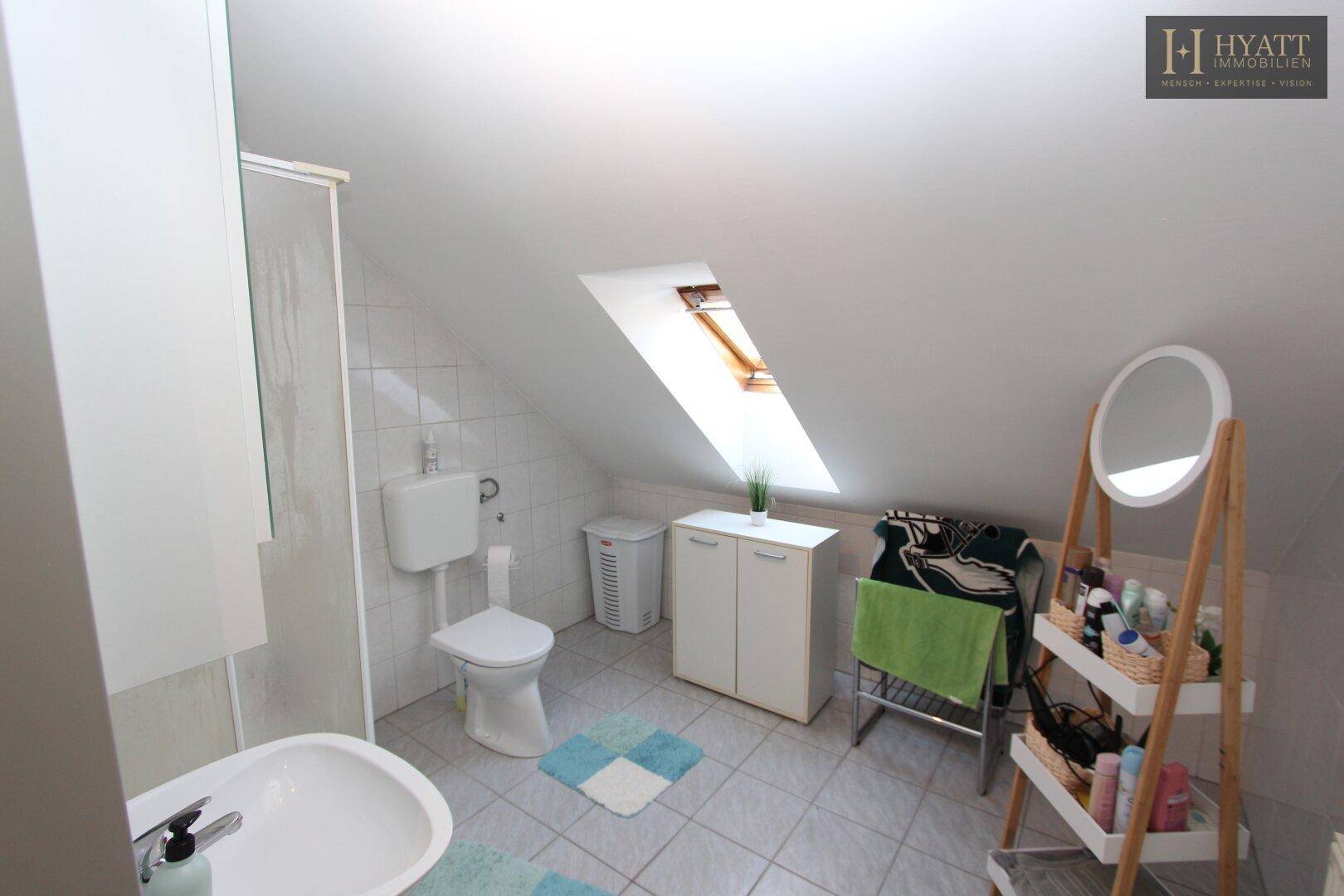 Helles Badezimmer im Dachgeschoss mit Dusche, WC und Dachfenster.