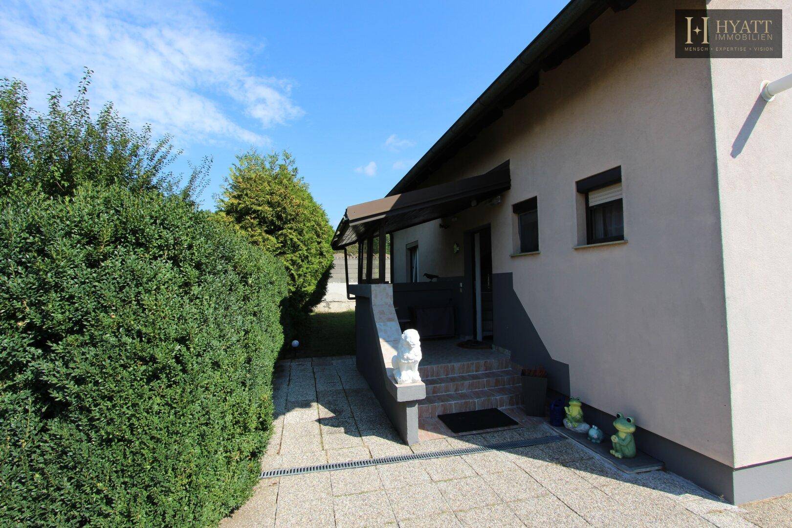 Eingangsbereich des Hauses mit gepflastertem Vorplatz und dekorativen Figuren.