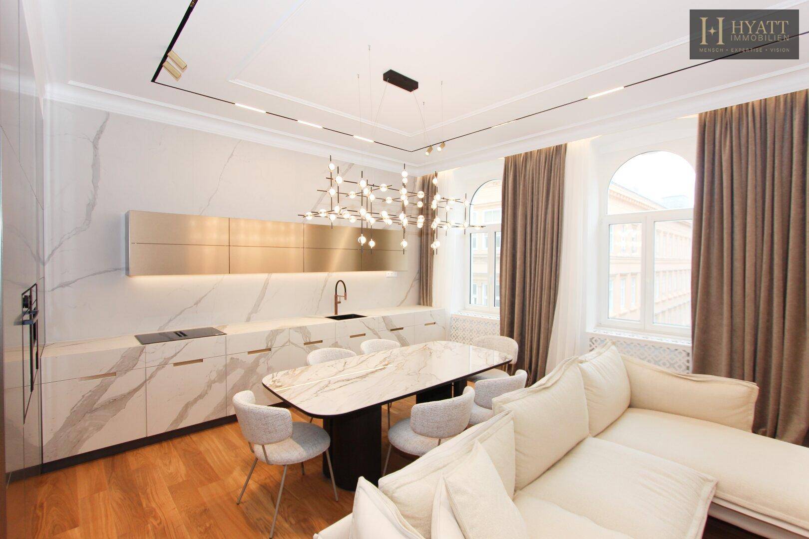 Heller Wohn- und Essbereich mit offener Küche, Marmoroberflächen und großen Fenstern.