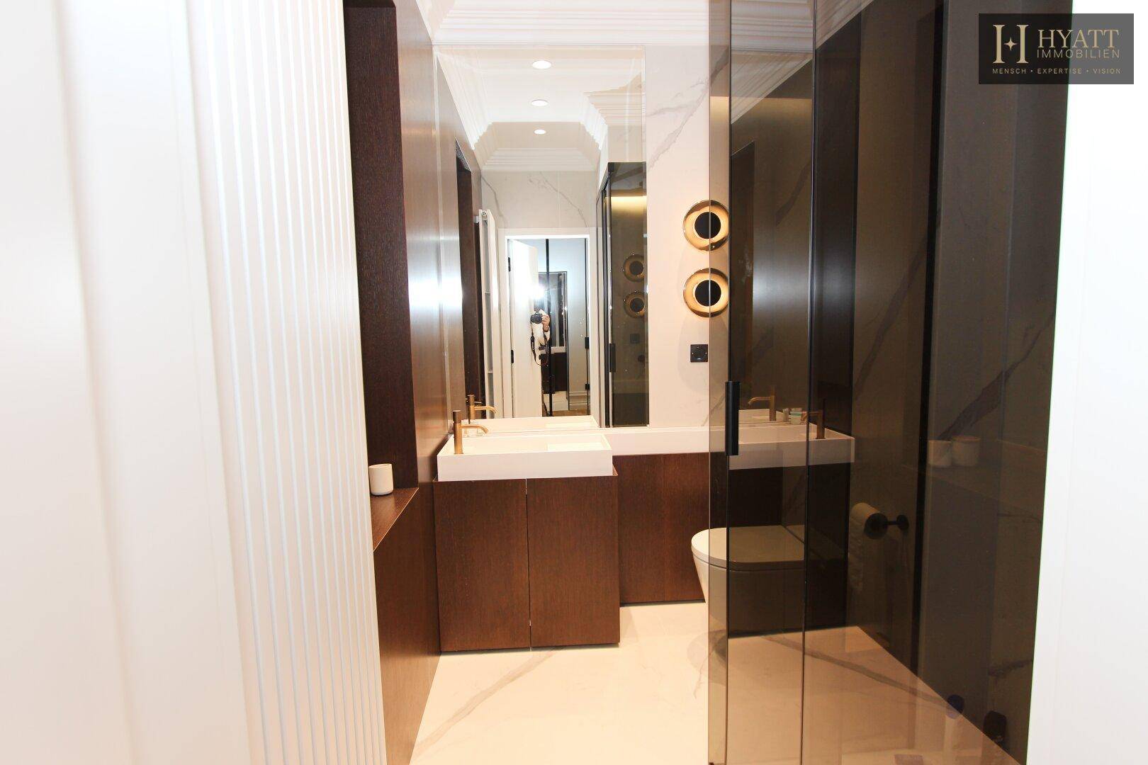 Modernes Gäste-WC mit dunklen Holzmöbeln, weißem Waschbecken und Spiegel.