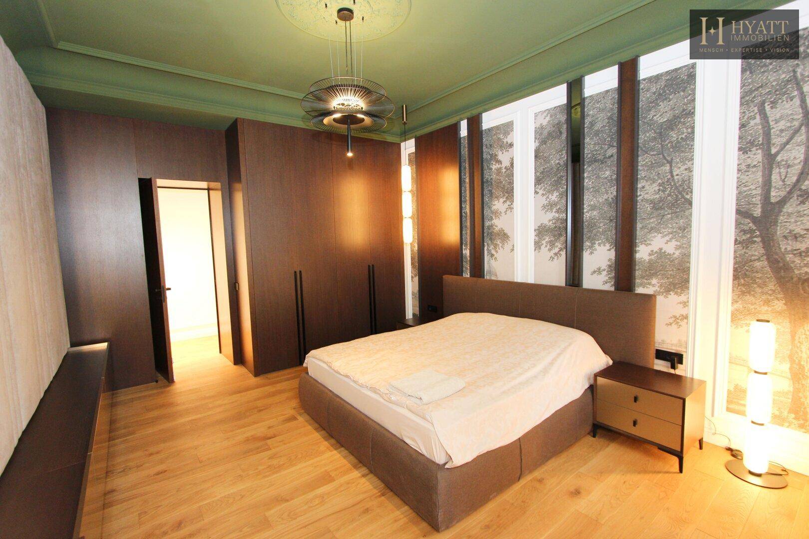 Helles Schlafzimmer mit Holzboden, Einbauschränken und großen Fenstern.