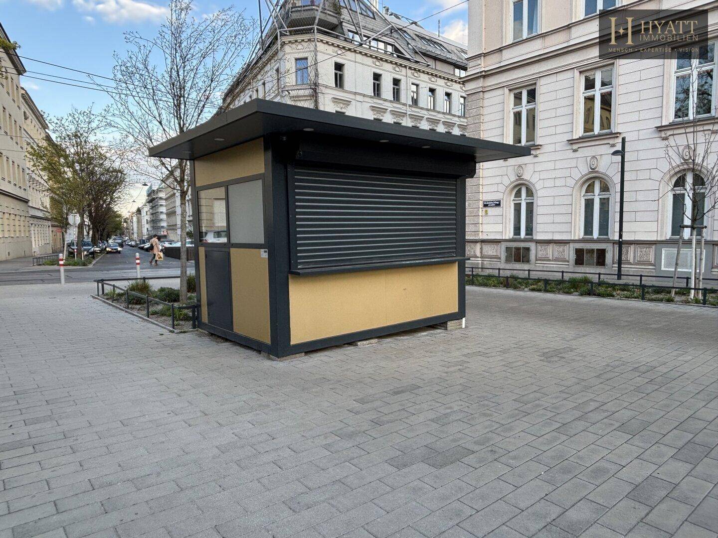 Der Kiosk ist geschlossen, mit heruntergelassenen Rollläden und einer schlichten Fassade.