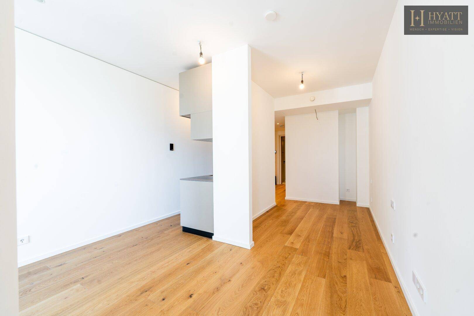 Geräumiger, lichtdurchfluteter Wohnbereich mit Parkettboden und minimalistischer Ästhetik, ideal für moderne Einrichtung.