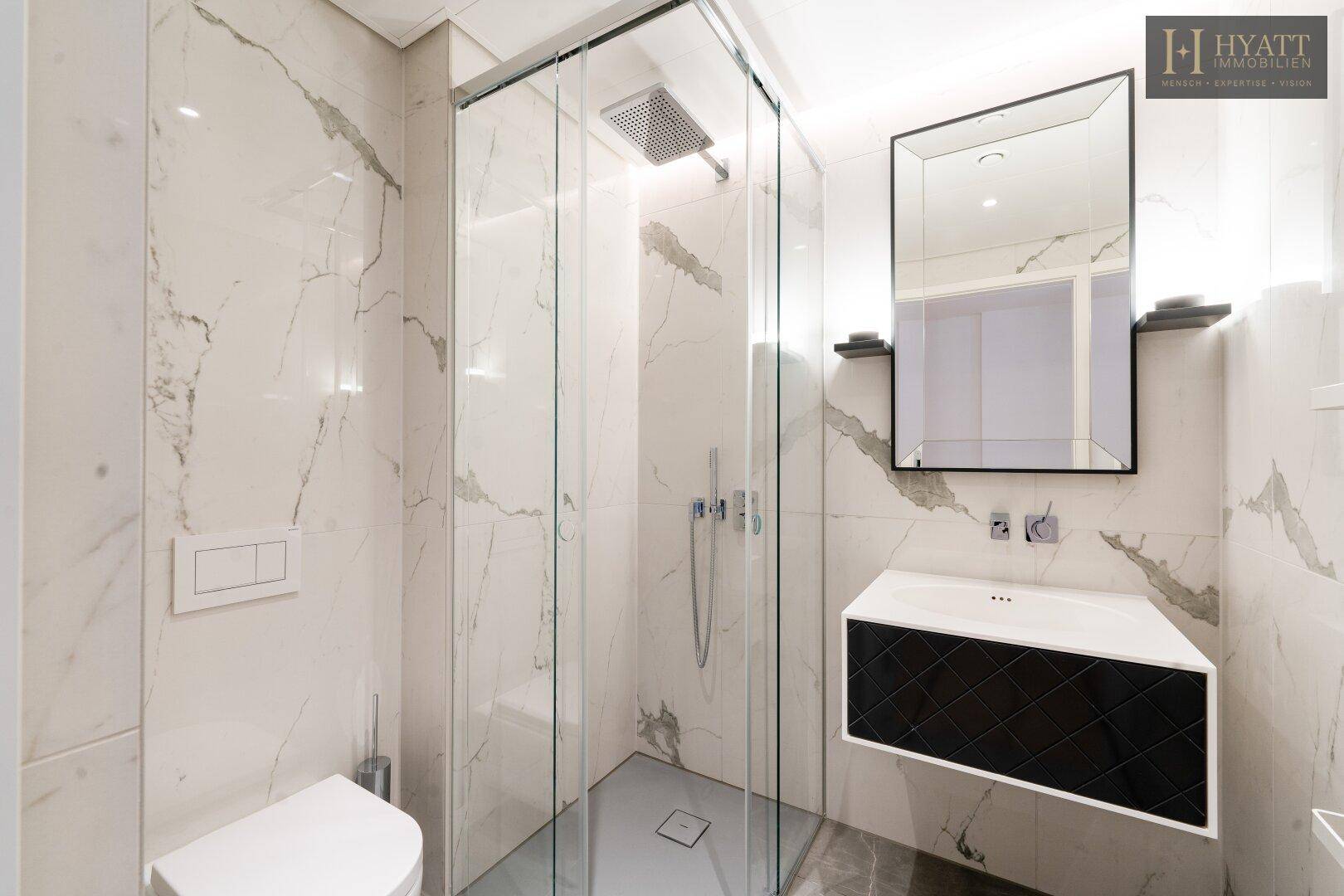Luxuriöses Badezimmer mit Marmorfliesen, einer geräumigen begehbaren Dusche und modernem Waschtisch.