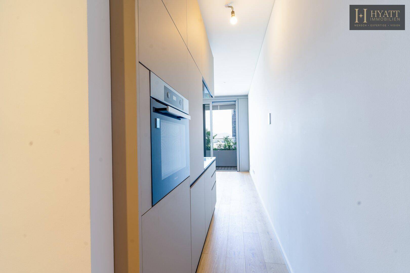 Funktionale Küchenzeile mit Einbaugeräten und direktem Zugang zu einem Balkon im Hintergrund.