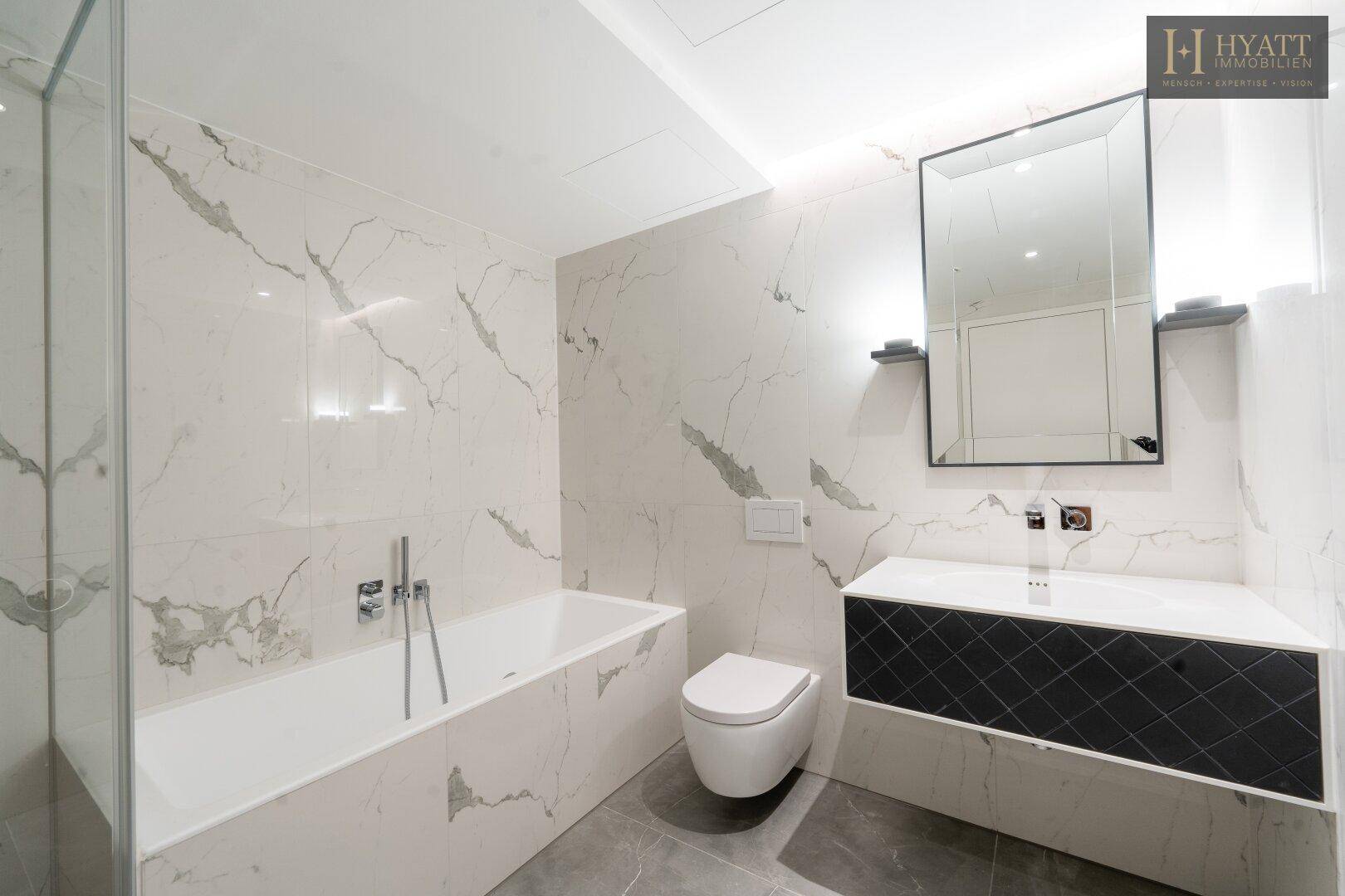 Modernes Badezimmer mit Marmorfliesen, Badewanne und elegantem Waschtisch mit Spiegel.
