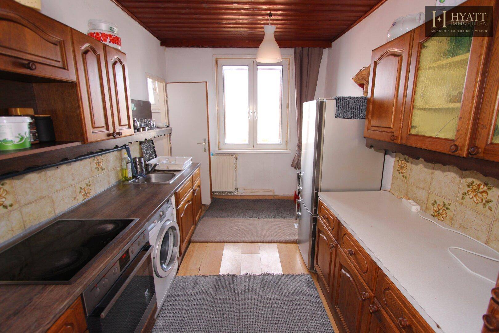 Traditionelle Küche mit Holzschränken, gefliestem Spritzschutz und Holzbalkendecke.