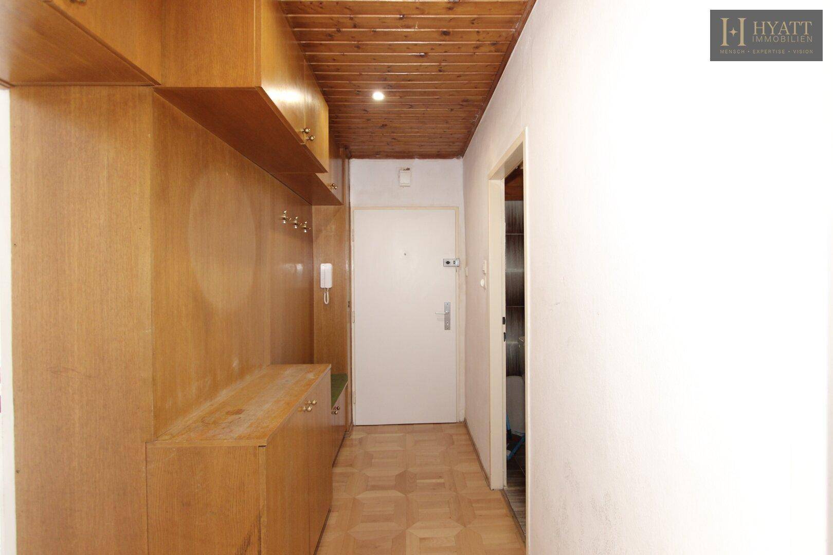 Flur mit Holzvertäfelung, Einbauschränken und Parkettboden, führt zur Eingangstür.