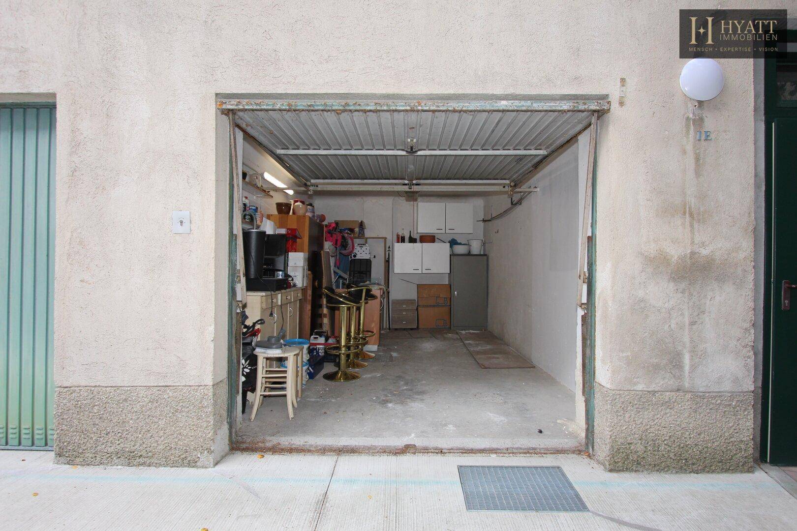 Offene Garage mit Stauraum und verschiedenen Gegenständen im Inneren.