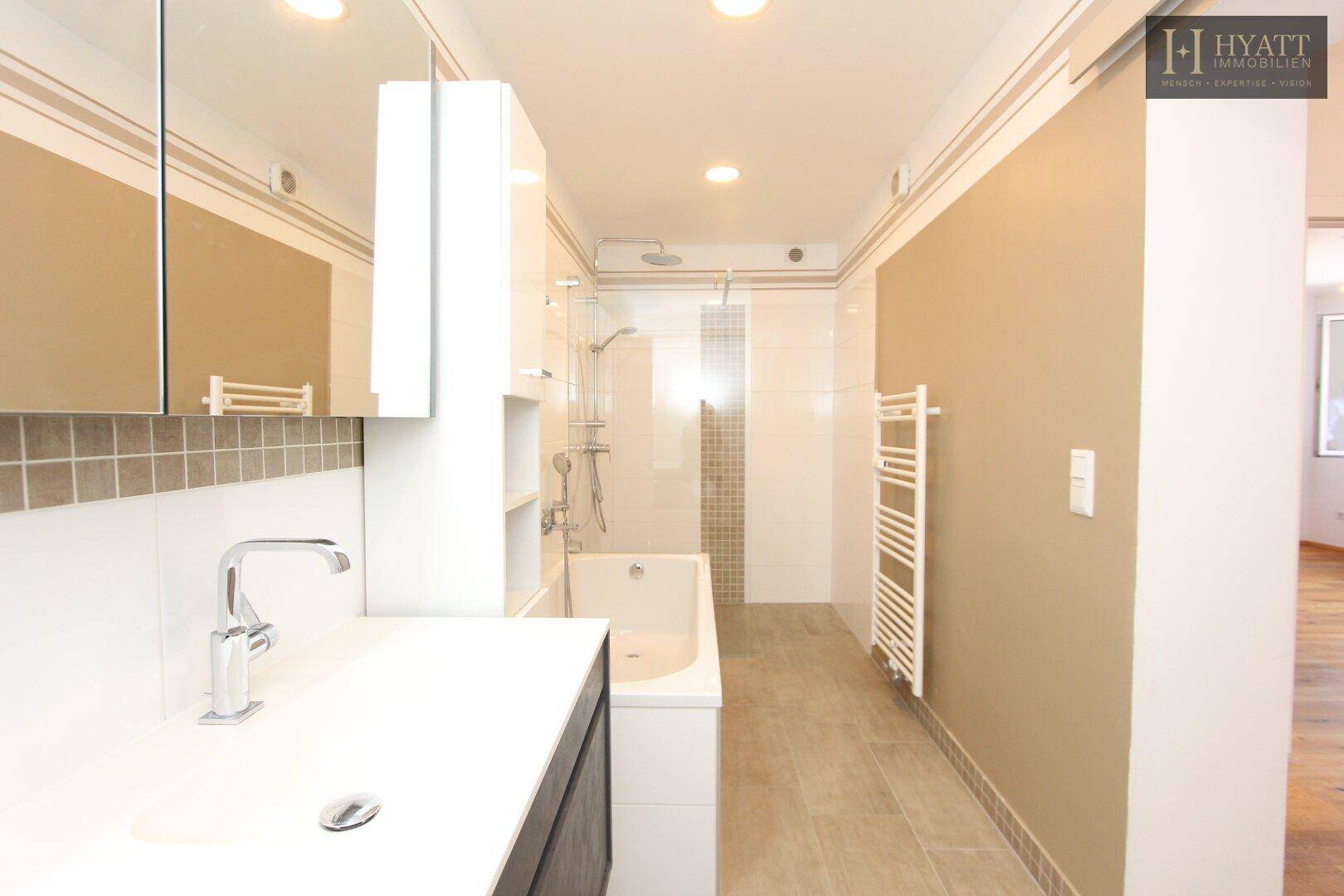 Modernes Badezimmer mit Badewanne, Dusche, Einzelwaschbecken und beheiztem Handtuchhalter.