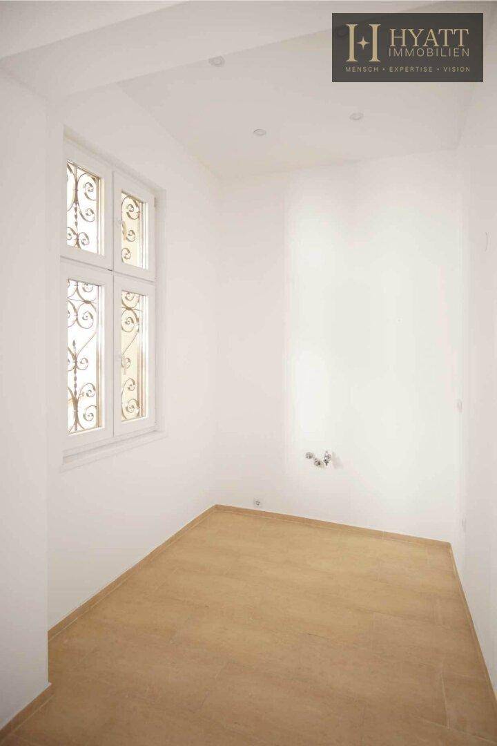 Unmöblierte Küche mit Holzboden und Fenster, bereit für die Installation einer Einbauküche.