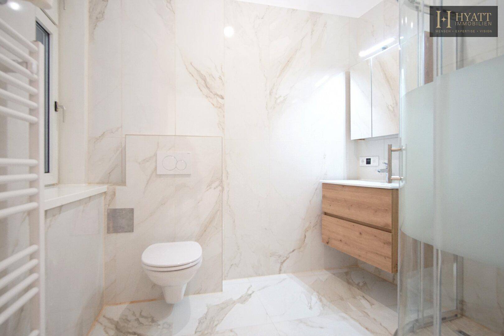 Modernes Badezimmer mit Marmorfliesen, wandhängendem WC und begehbarer Dusche.