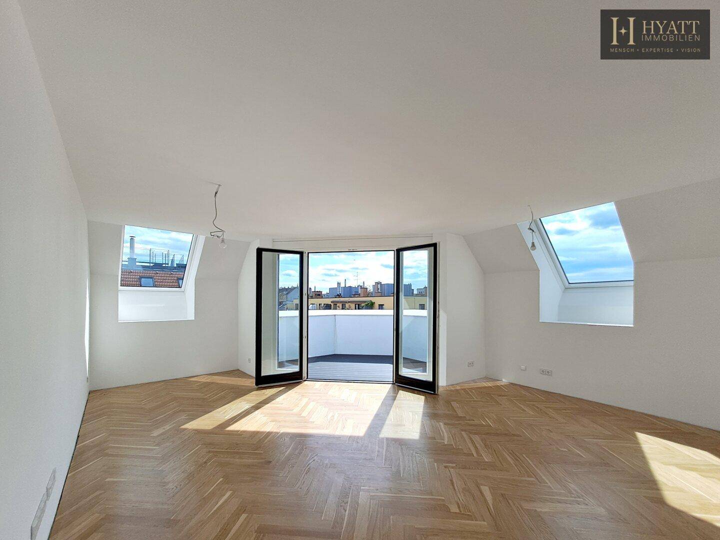Heller, leerer Wohn-Essbereich mit Fischgrätparkett, Dachfenstern und Terrassenzugang.