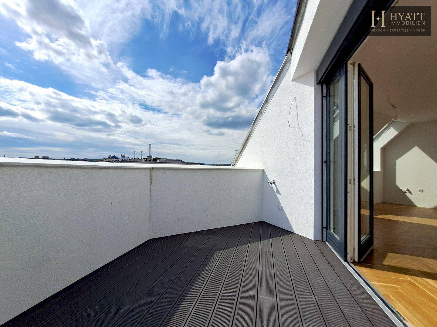 Leere Terrasse mit Holzdielenboden und weitem Blick auf die Umgebung.