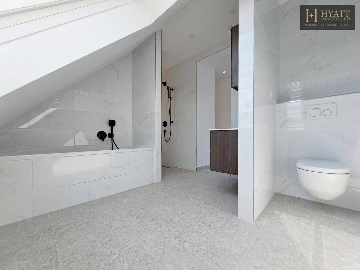 Geräumiges Badezimmer mit Badewanne, Dusche und wandhängendem WC.