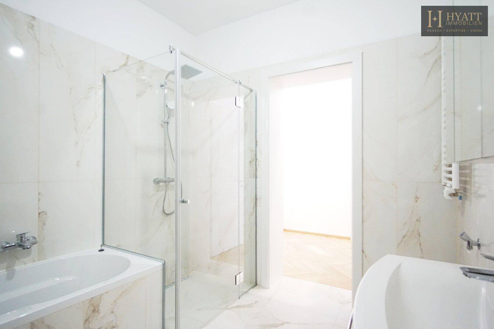 Modernes Badezimmer mit Badewanne, begehbarer Dusche und eleganten Marmorfliesen.