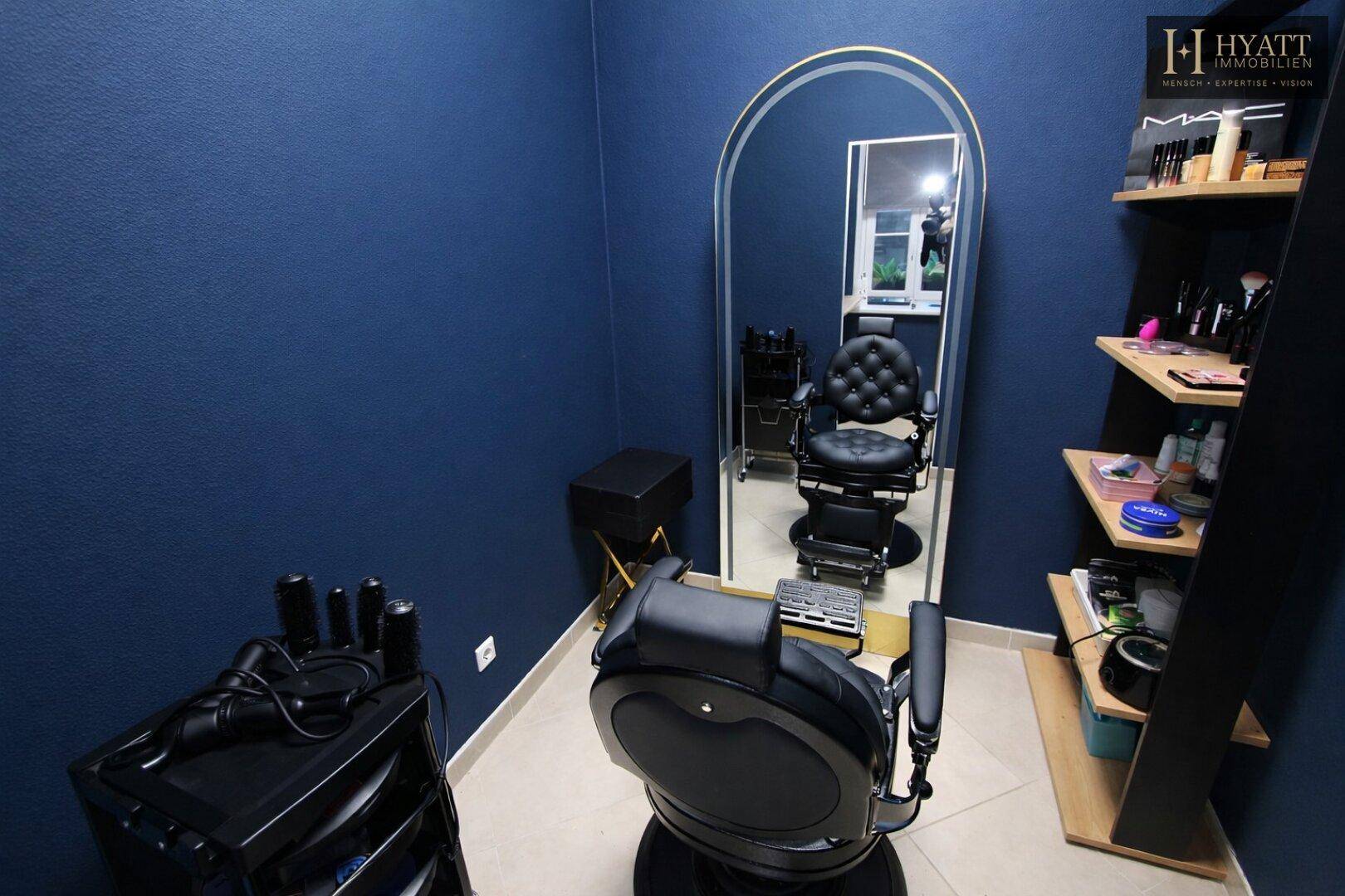 Friseurstuhl mit großem Bogen-Spiegel und Regalen für Stylingprodukte in einem modernen Salon.