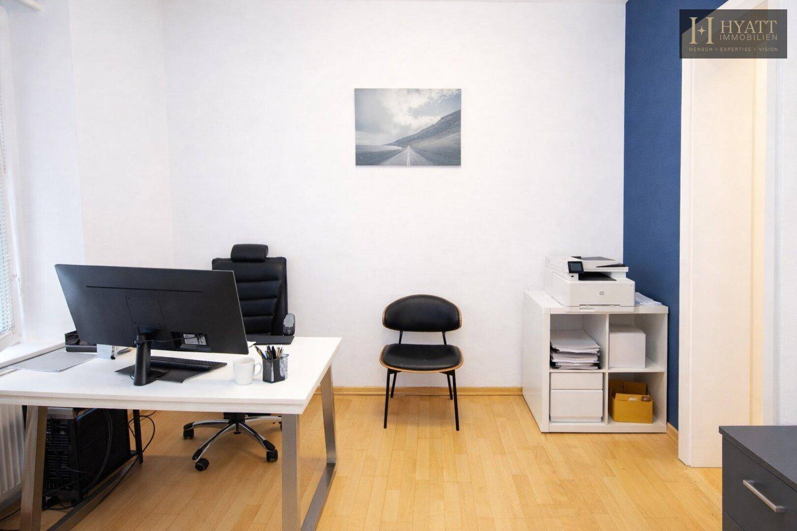 Helles Büro mit Schreibtisch, Bürostuhl und Drucker, ausgestattet für effizientes Arbeiten.