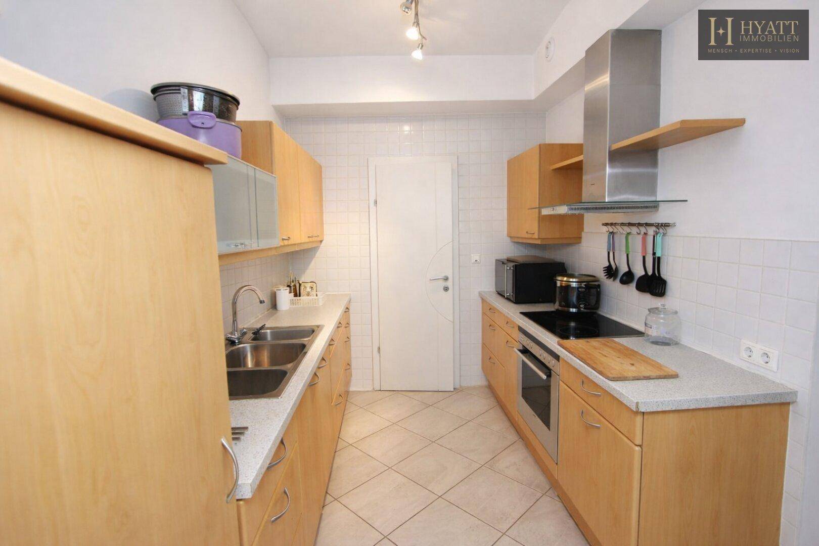 Funktionale Küche mit Holzschränken, Doppelspüle und modernen Geräten.