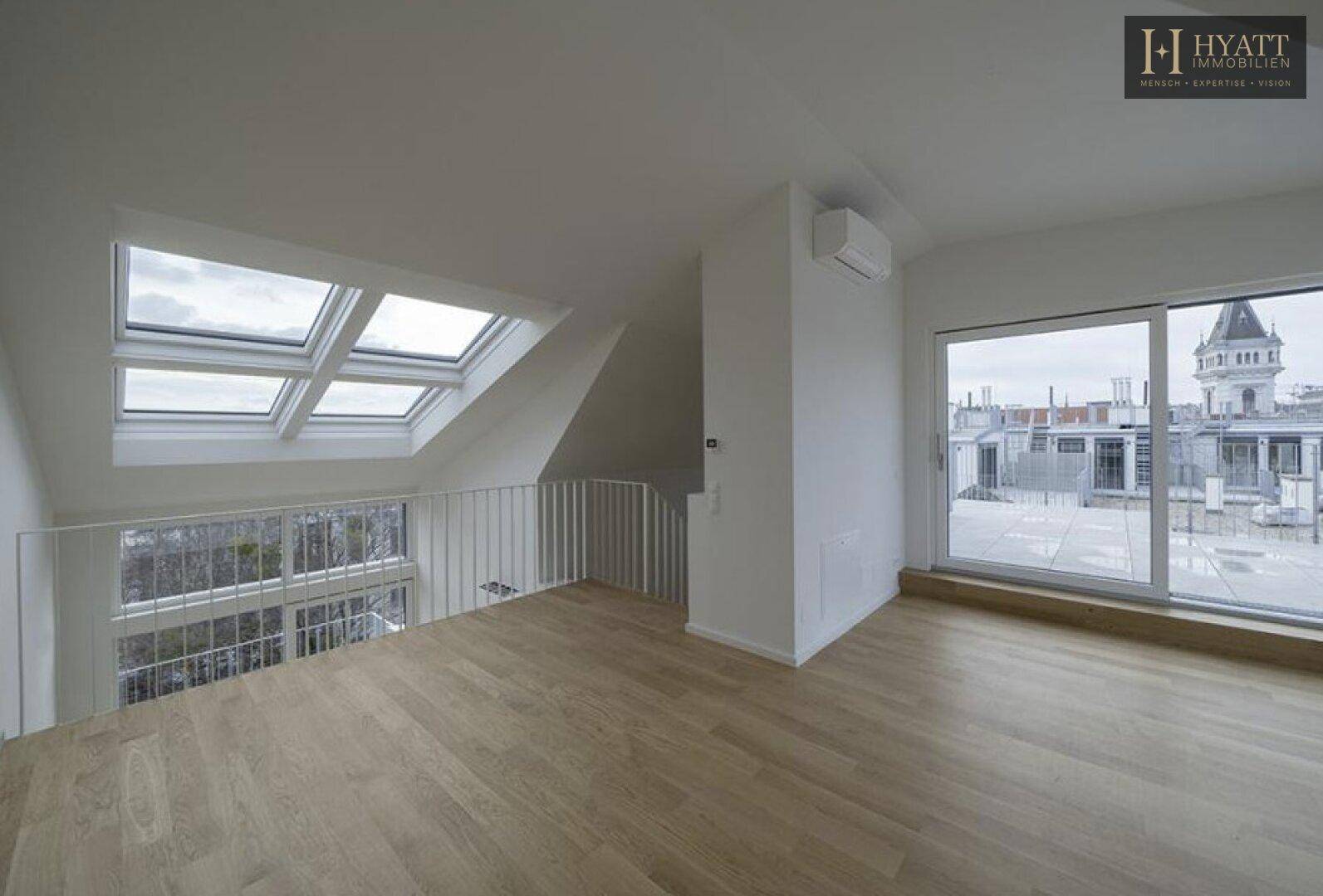 Offener Wohnbereich mit Holzfußboden, Galerie und großen Fenstern mit Stadtblick.