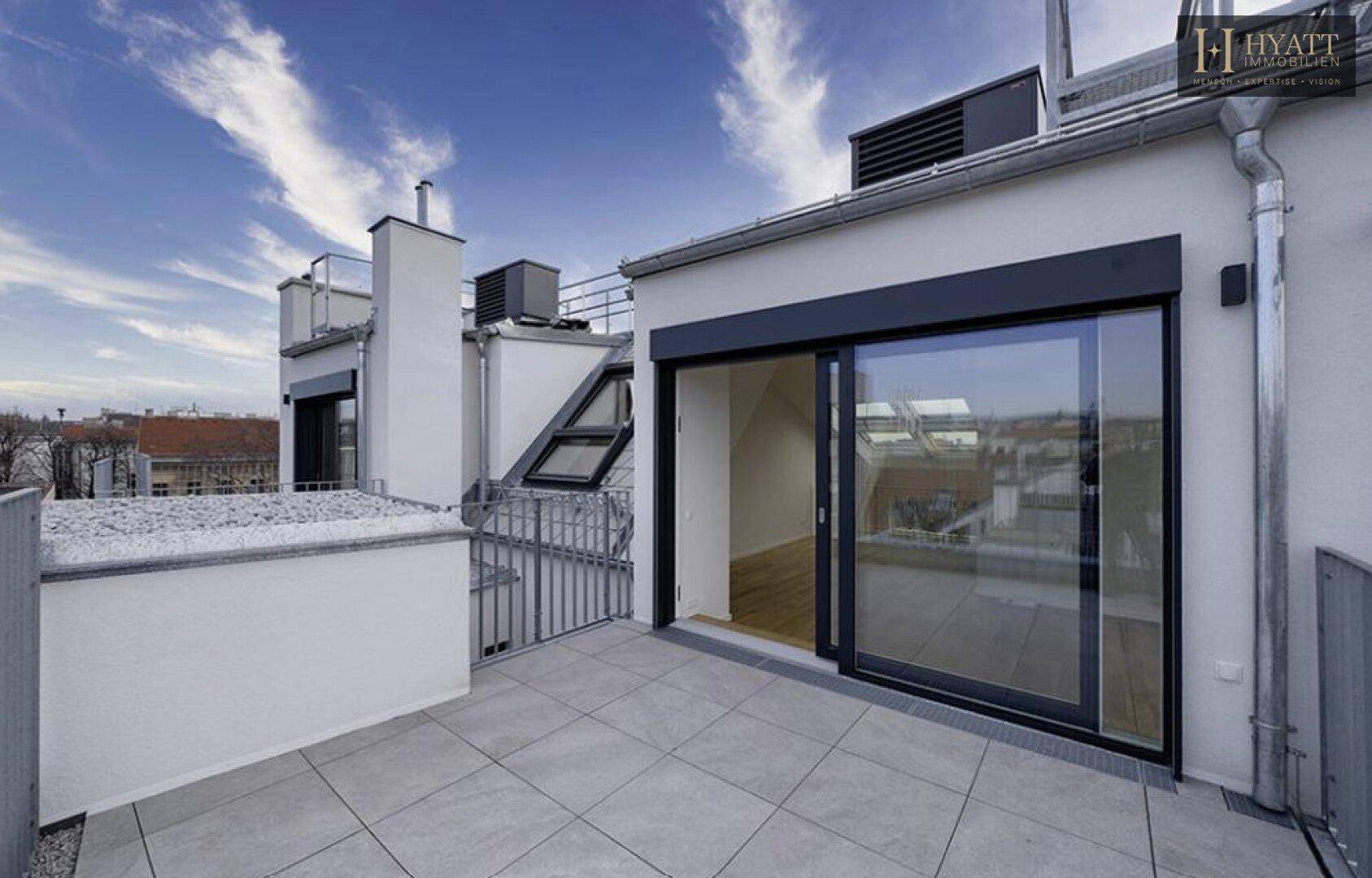Moderne Dachterrasse mit hellen Fliesen und Zugang zu den Innenräumen durch eine Glasschiebetür.
