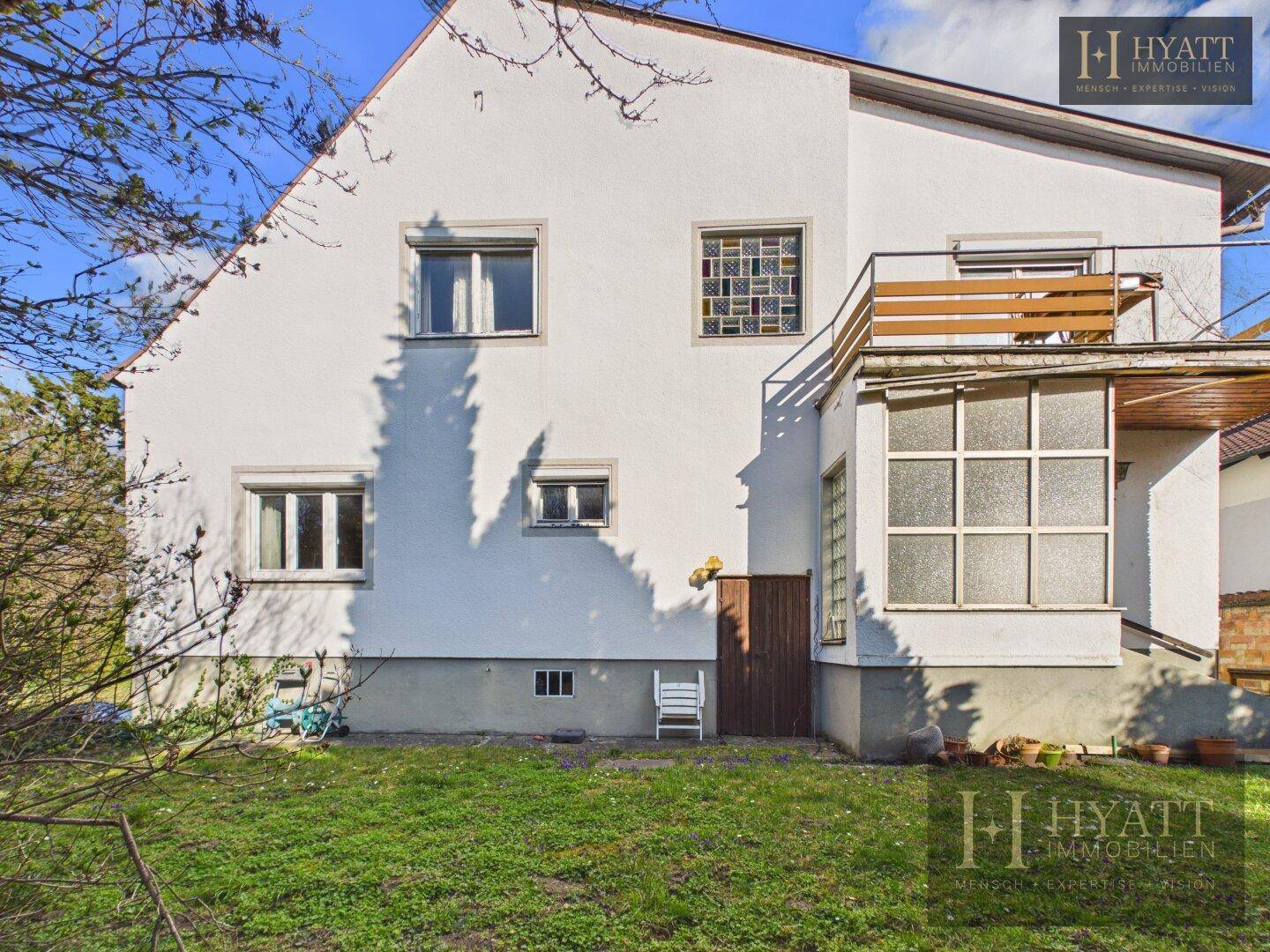 Seitenansicht des Hauses mit Balkon, Wintergarten und großem Gartenbereich.
