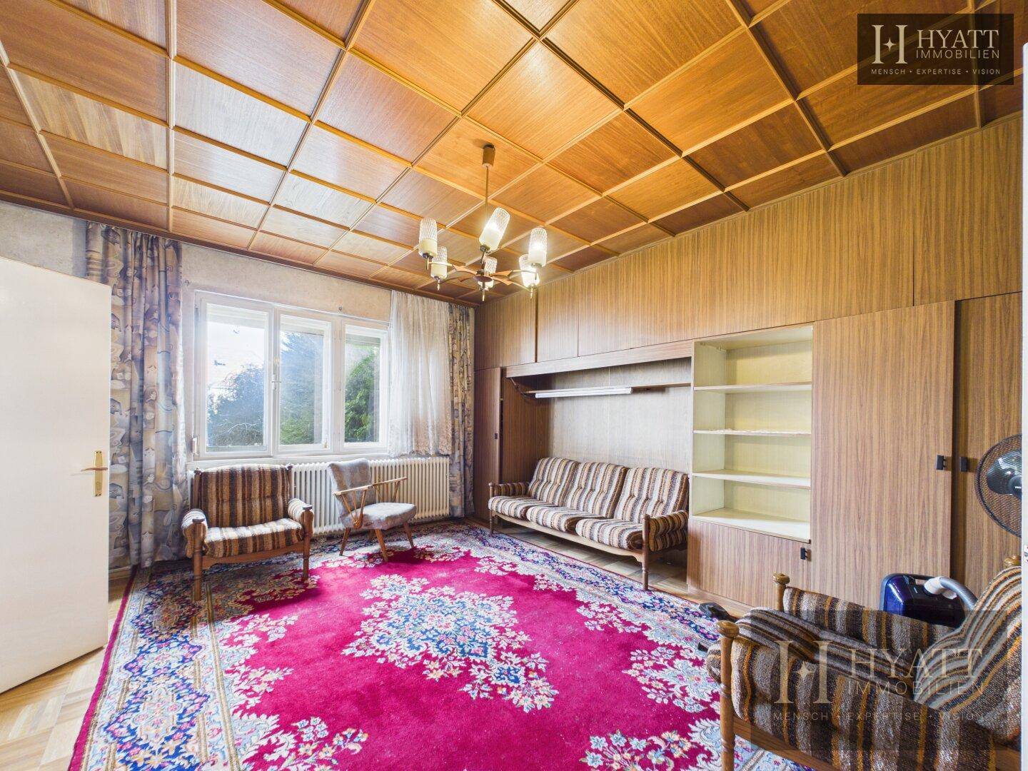 Geräumiges Zimmer mit Holzdecke, Einbauschränken und großem Fenster, das viel Licht bietet.