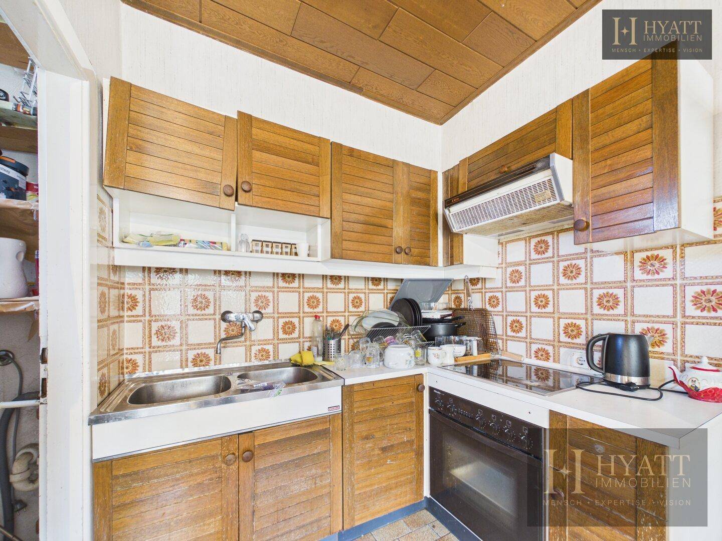Funktionale Küche mit Holzschränken, Doppelspüle und traditionellen Fliesen, die einen charmanten Look bietet.
