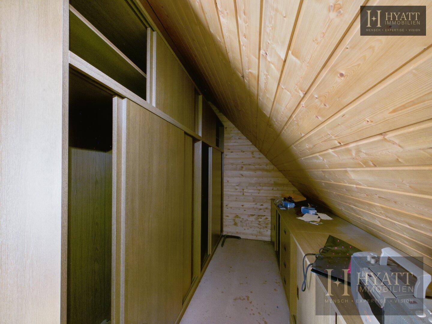 Geräumiger Dachboden mit Holzverkleidung und praktischen Einbauschränken für zusätzlichen Stauraum.