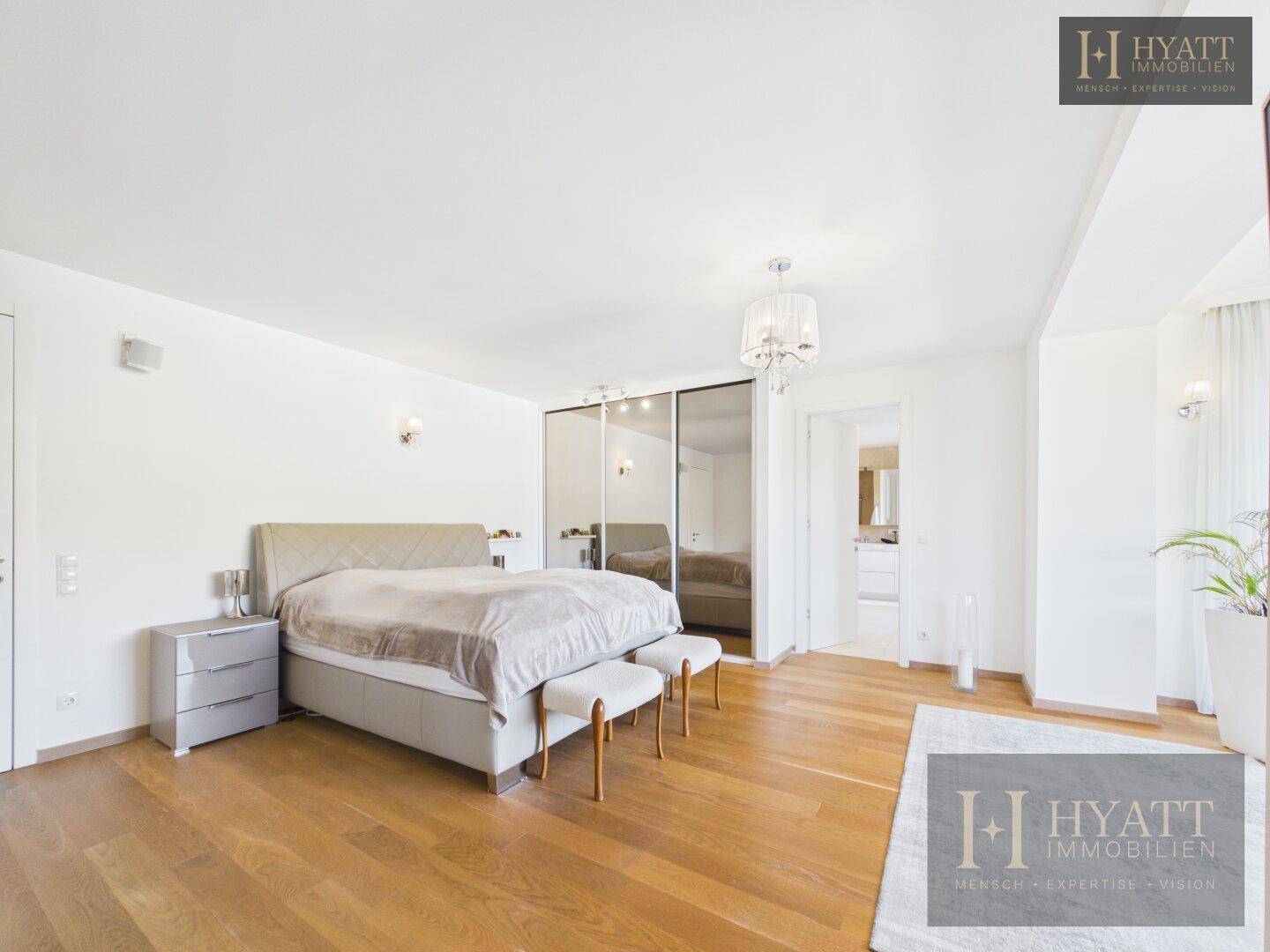 Elegantes Schlafzimmer mit Doppelbett, Holzboden und viel Tageslicht.