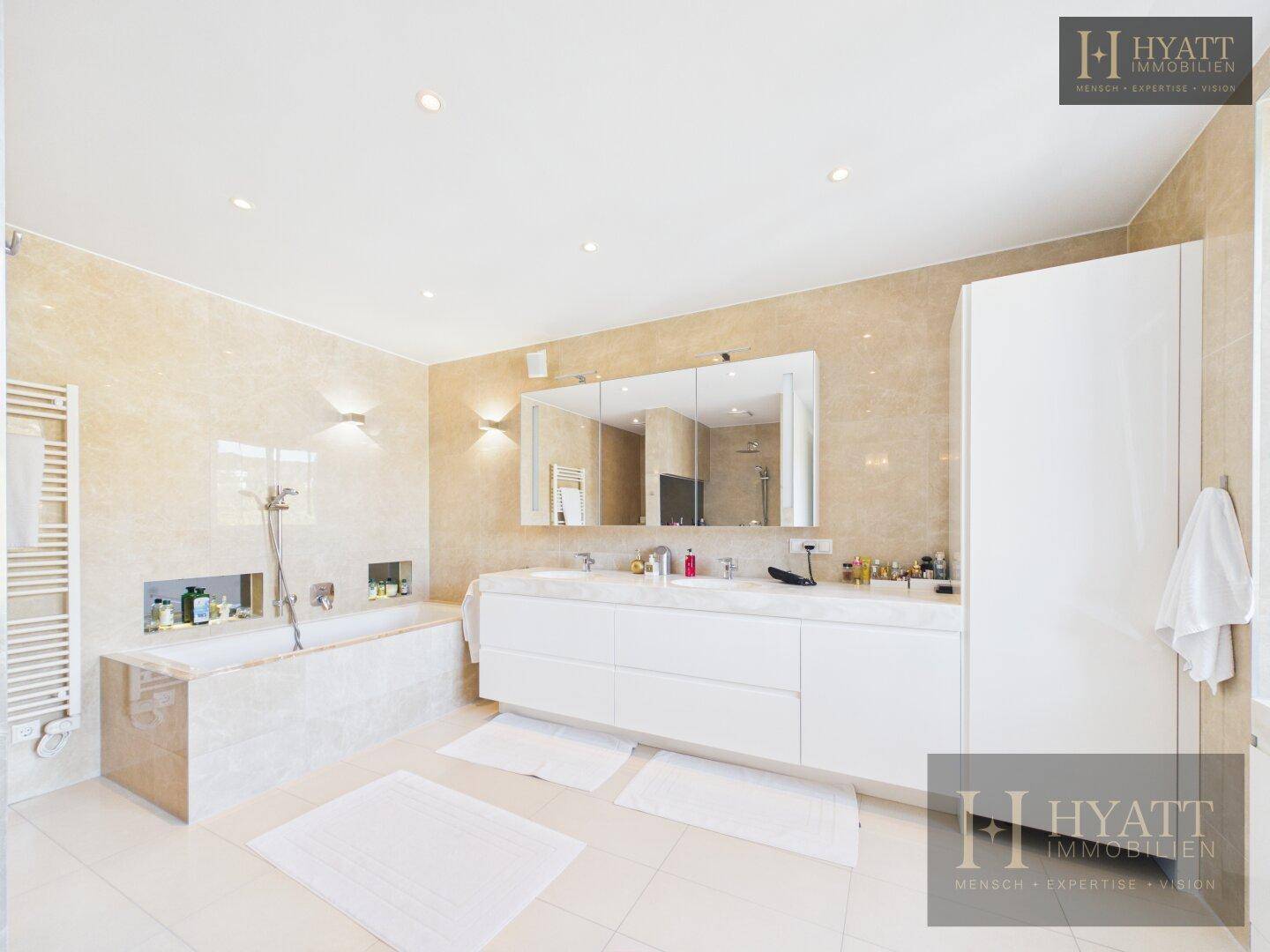 Luxuriöses Badezimmer mit großer Badewanne, Doppelwaschbecken und eleganten Marmorfliesen.