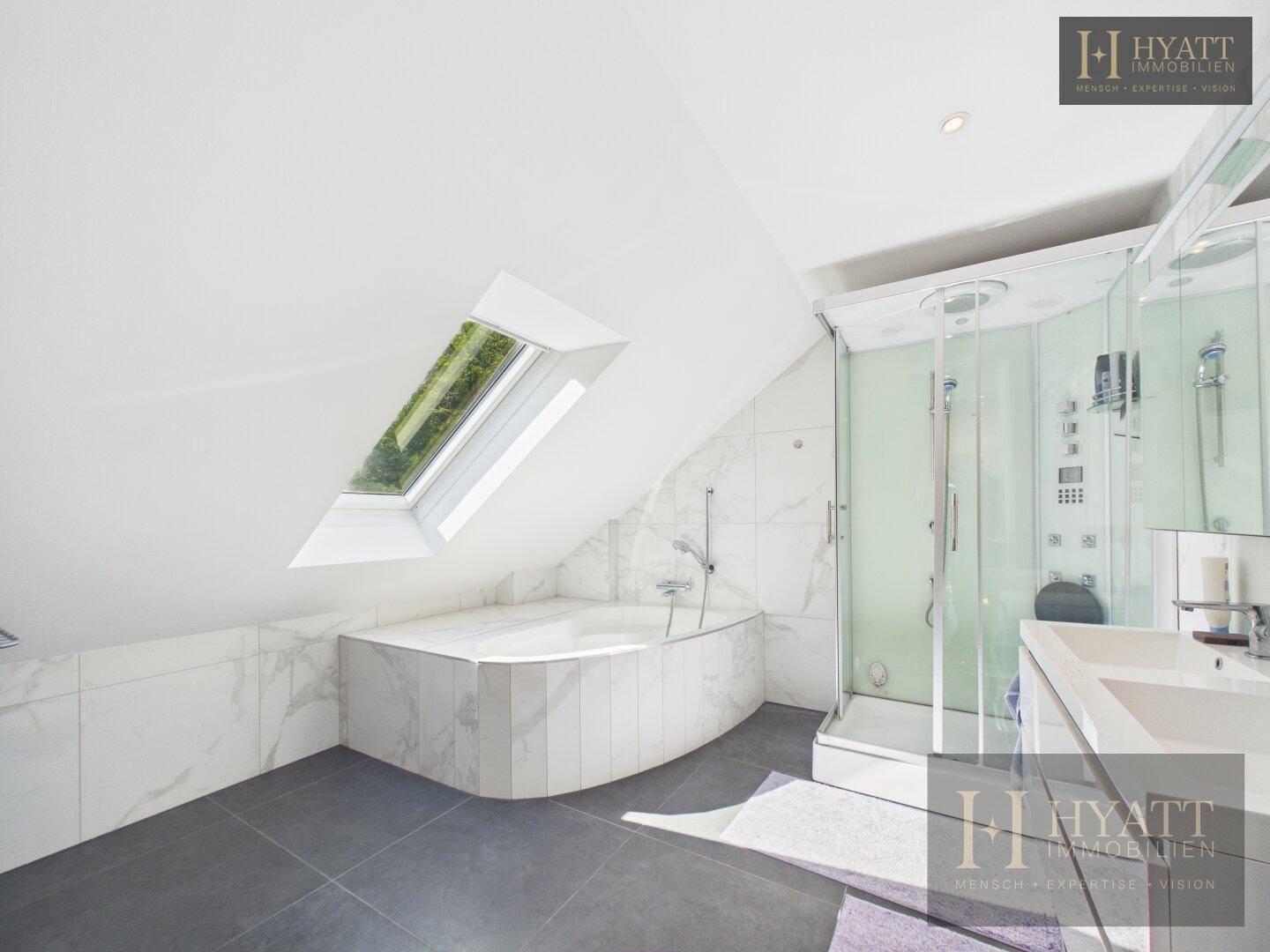 Modernes Dachbad mit Badewanne, Duschkabine und Dachfenster für natürliches Licht.