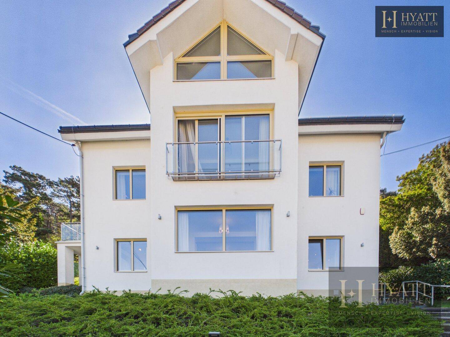 Moderne Hausfassade mit großen Fenstern und einem französischen Balkon.