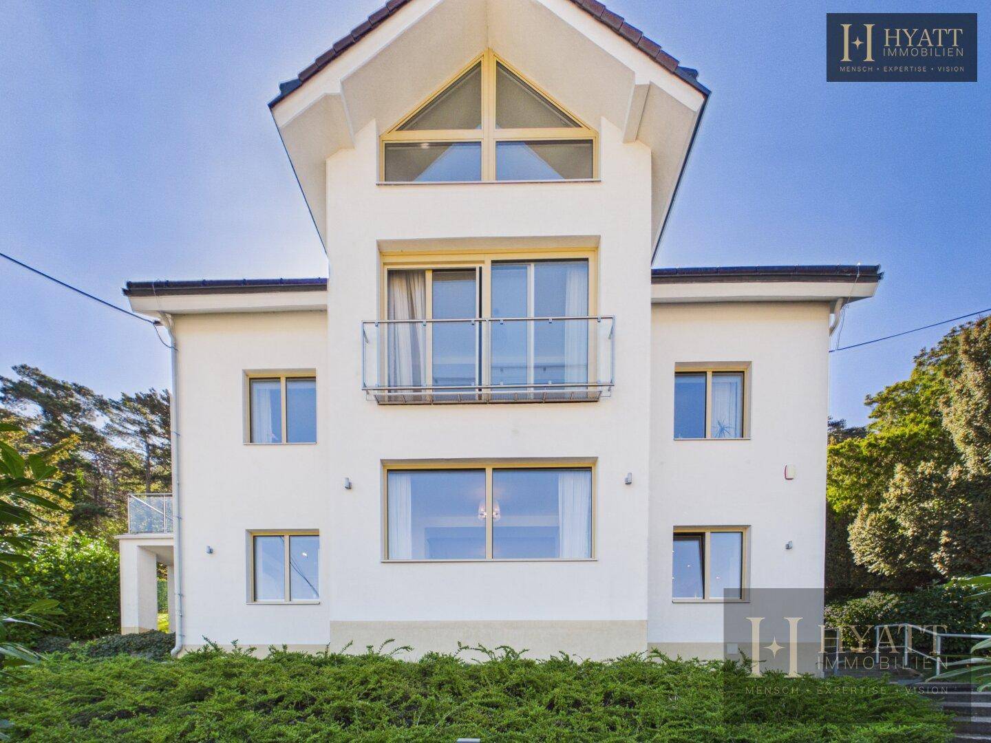 Moderne Hausfassade mit großen Fenstern und einem französischen Balkon.