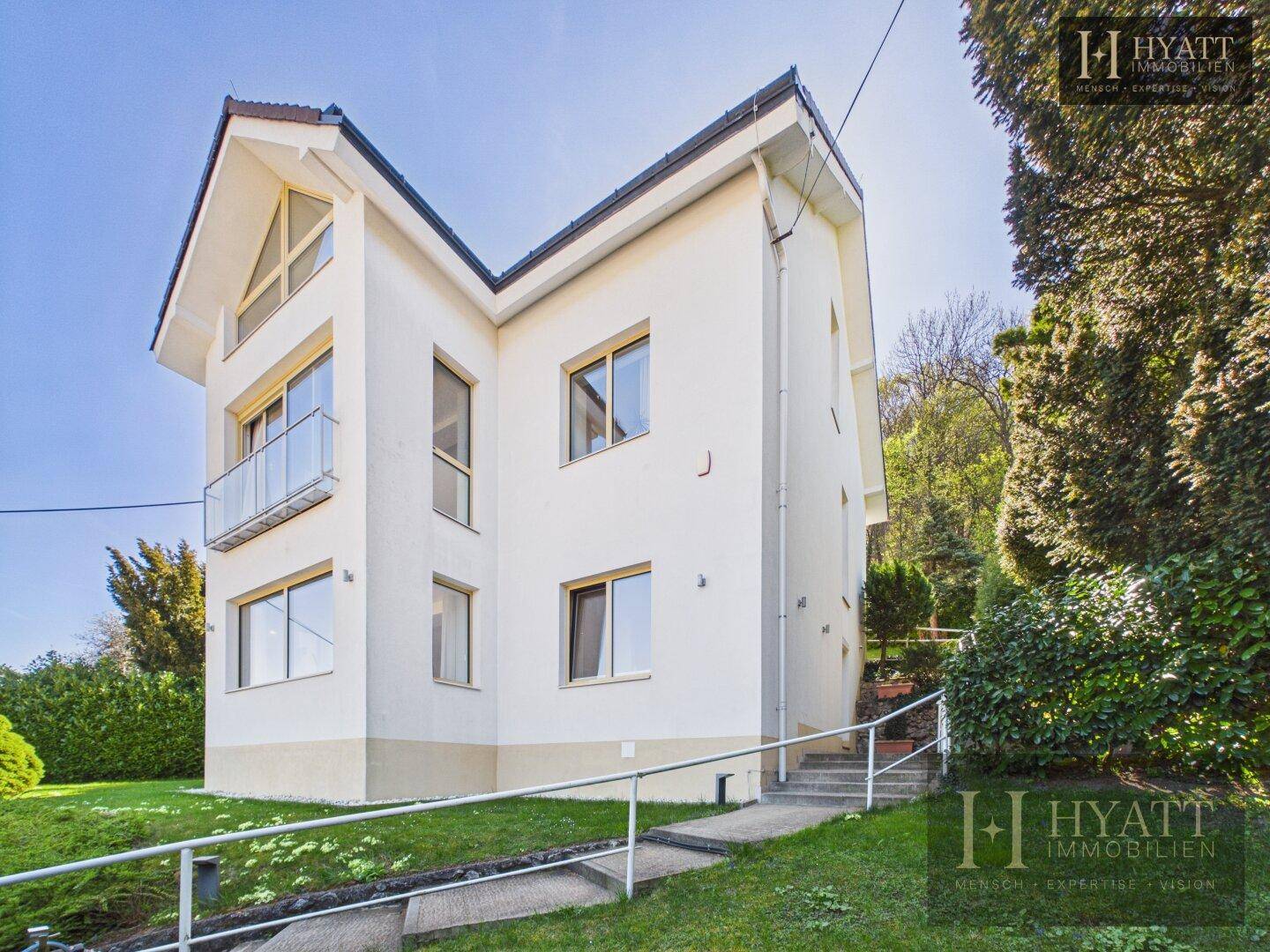 Seitenansicht des Hauses mit Zugang über eine Rampe und Treppen im Grünen.