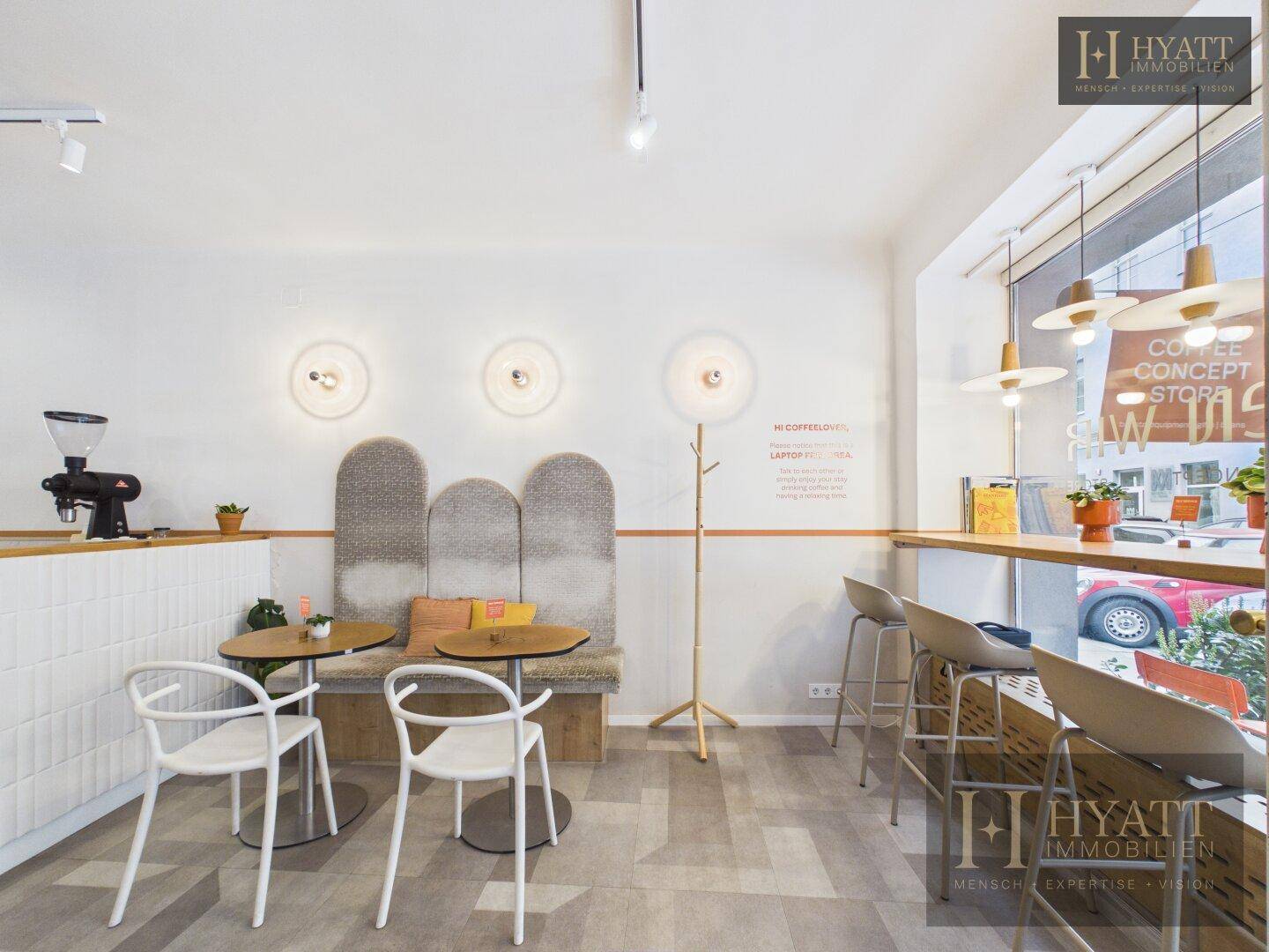 Heller Sitzbereich in einem Concept Store mit modernen Möbeln und großen Fenstern zur Straßenseite.