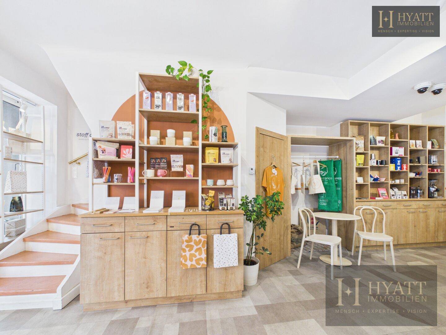 Verkaufsbereich eines Concept Stores mit Holzregalen, einer Treppe und einem kleinen Sitzbereich.