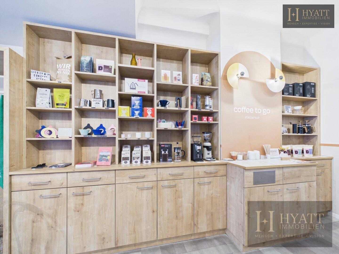 Umfangreiche Holzregale mit Produkten und einer Kaffeestation in einem modernen Concept Store.