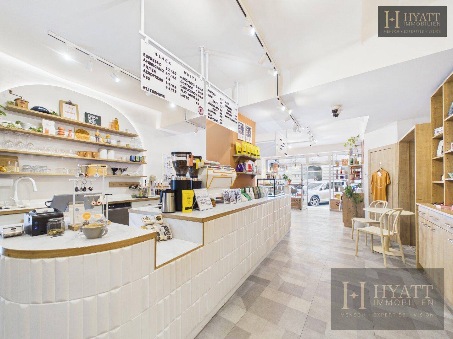 Haupttheke eines Concept Stores mit Kaffeebar, Preistafel und Blick auf den Eingangsbereich.