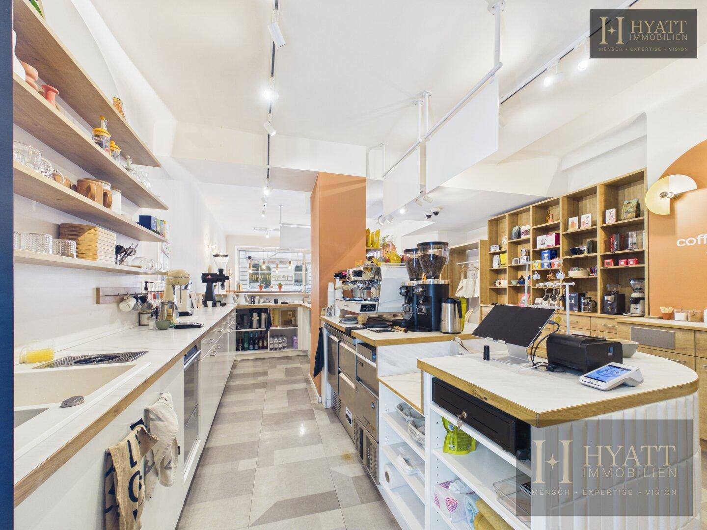 Arbeitsbereich hinter der Theke mit Spüle, Regalen und Kaffeemaschinen in einem Concept Store.