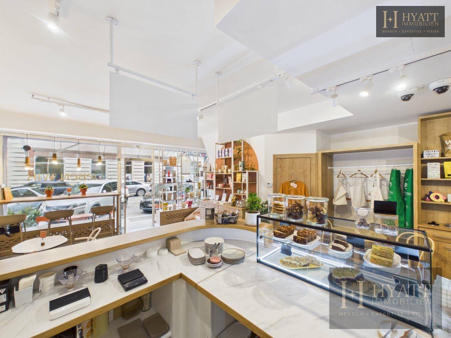 Thekenbereich mit Kuchenvitrine, Kaffeemaschinen und Blick auf den Eingangsbereich des Concept Stores.