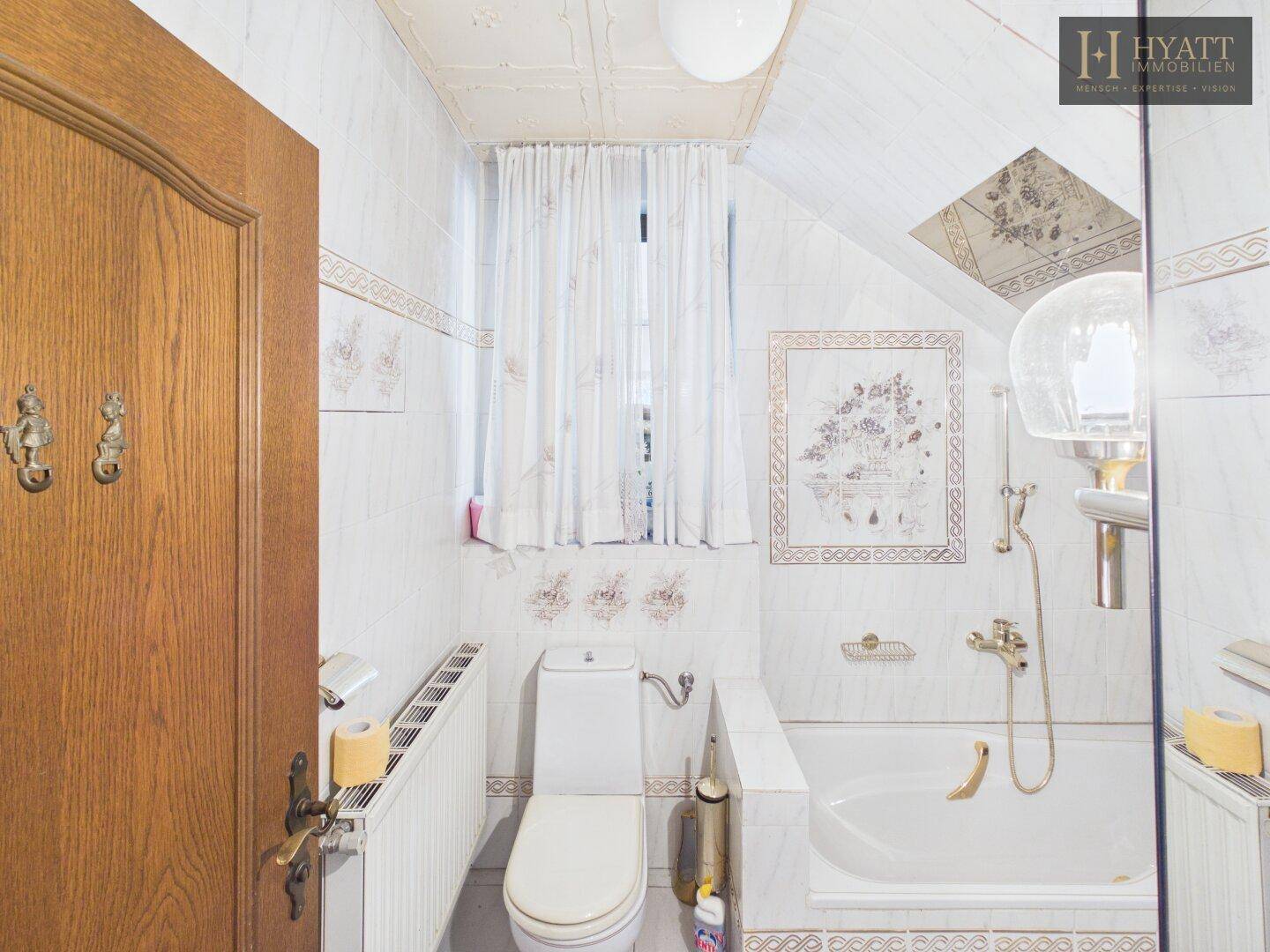 Badezimmer mit Badewanne, WC und Fenster, ausgestattet mit Heizkörper.
