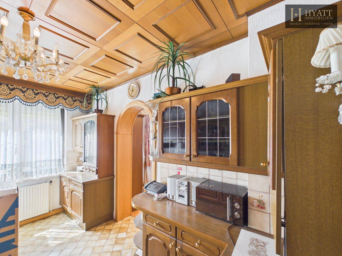 Gemütliche Küche mit Holzmöbeln, Fliesenboden und dekorativer Holzdecke.
