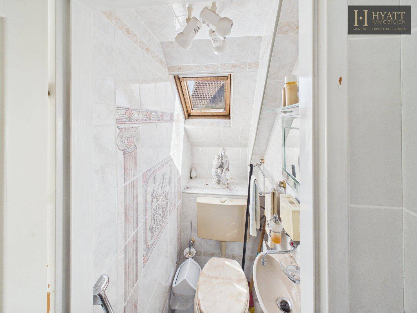 Kleines WC im Dachgeschoss mit Dachfenster und schrägen Wänden.