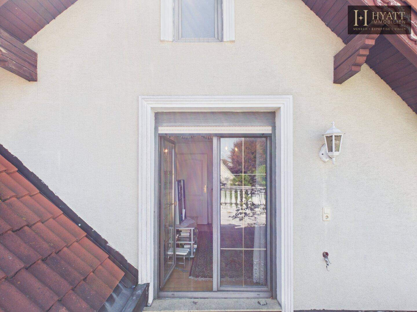 Fassade des Hauses mit Dachschräge und Ausgang zu einem Balkon oder Terrasse.