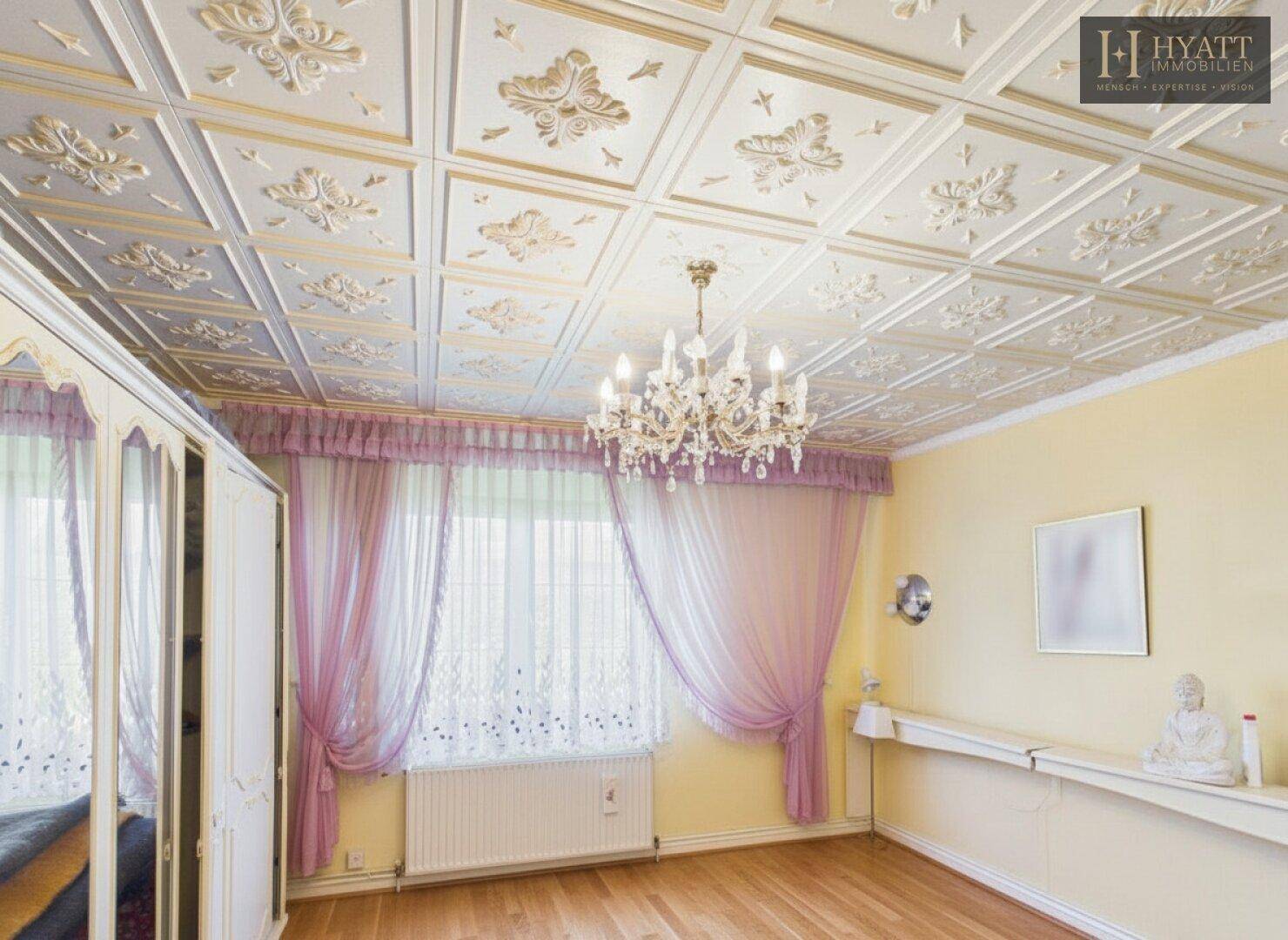 Geräumiges Zimmer mit Holzboden, dekorativer Decke und großem Fenster.